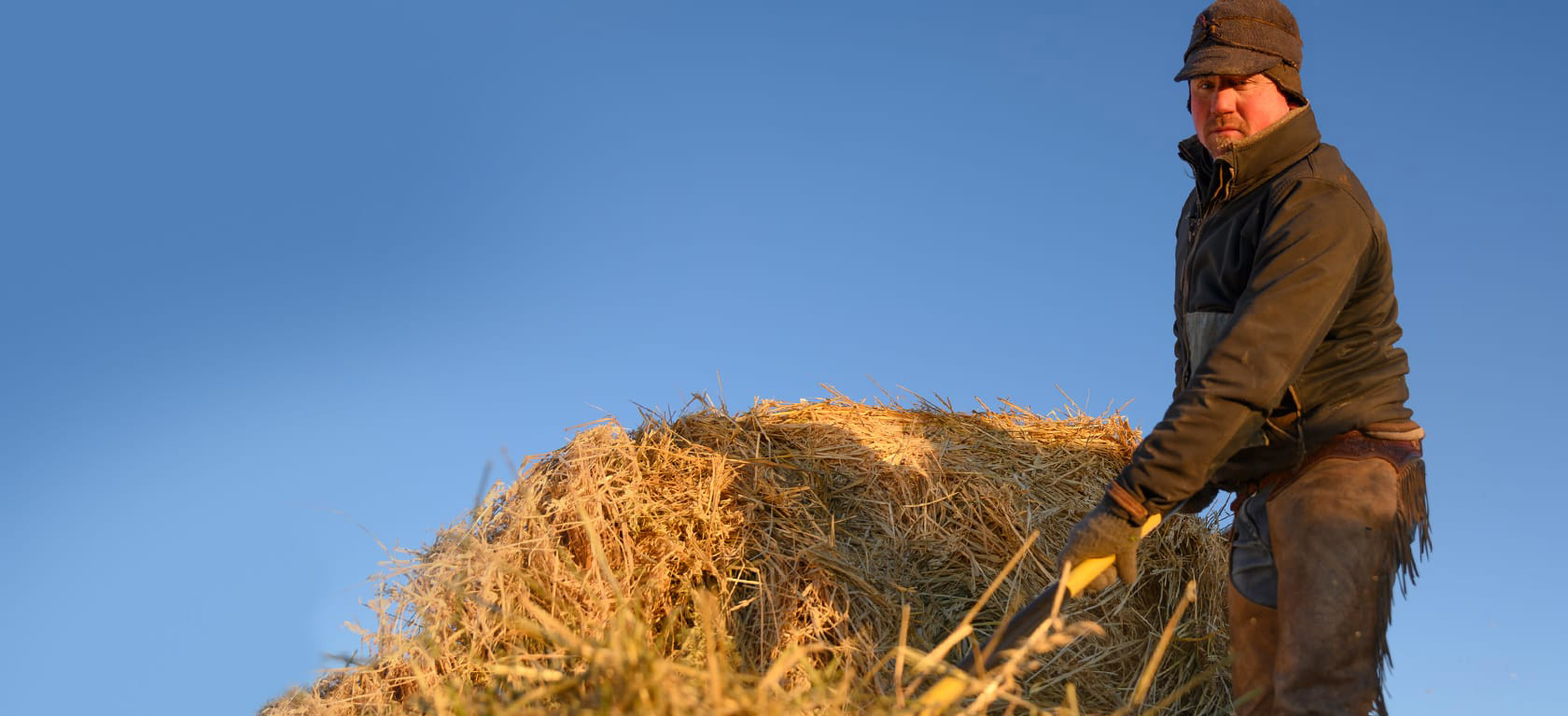 rancher carrying a hay bale