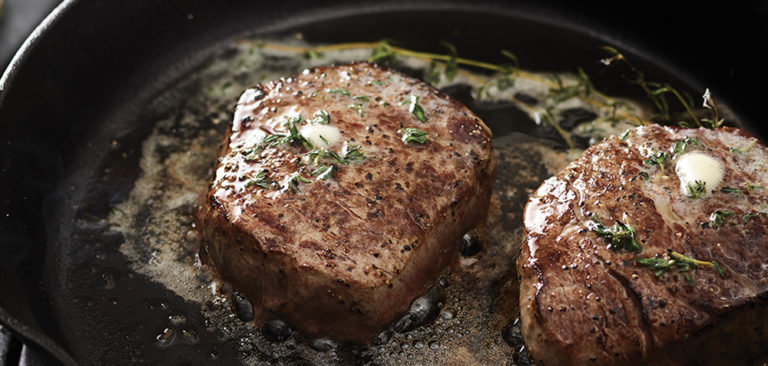 steaks cooking in butter and herbs