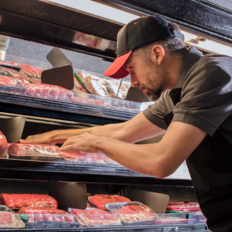 worker places beef products in meat case